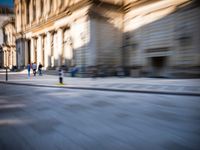 a blurry photo of a person in front of an old building, a man on a skateboard riding down the street