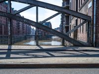 a metal gate with no one on it over an alley with buildings and water behind it