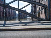 a metal gate with no one on it over an alley with buildings and water behind it