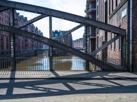 a metal gate with no one on it over an alley with buildings and water behind it