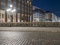 a view of some buildings in a city street at night with a man riding a bike