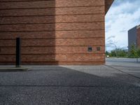 an image of a brick building near the street outside of a city center area,