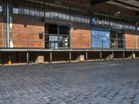 a bicycle parked outside of the side of an old building with benches and barriers around it