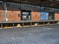 a bicycle parked outside of the side of an old building with benches and barriers around it