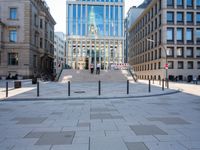 a sidewalk that has a long curved walkway and several buildings behind it in the city