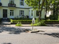 a street sign is in the middle of the road in front of a house with large windows