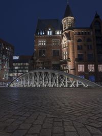 a large brick building sitting next to a brick road under a bridge with lights on