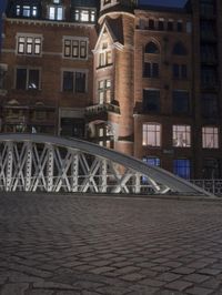 a large brick building sitting next to a brick road under a bridge with lights on