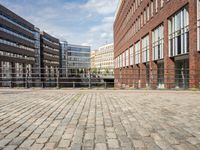 a courtyard with brick and metal railings that are open to the view in front of some buildings