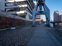 the sidewalk that leads up to the tall building behind it on a clear day, with a clock tower above