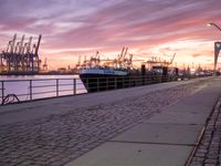 the evening sky above ships and dock on the waterfront at dusk as the sun sets