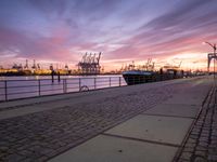 the evening sky above ships and dock on the waterfront at dusk as the sun sets