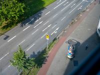 a street view from above with a bus driving down it's middle lane, next to a park