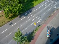 a street view from above with a bus driving down it's middle lane, next to a park