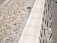 some people are walking along a path beside water and buildings with brick walls and plants in the foreground