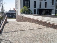 a brick walkway with no cars on it next to buildings along the river bank in downtown