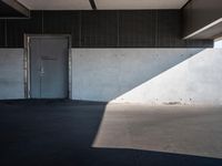 an empty building with a door and a wall with some light on it is empty and has a white door