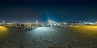 a 360 lens photograph of the walkway and plaza at night with light reflecting on the sidewalk