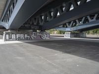 a large graffiti piece on the underside of a bridge with many smaller graffiti pieces attached to it