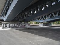 a large graffiti piece on the underside of a bridge with many smaller graffiti pieces attached to it