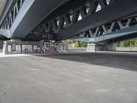 a large graffiti piece on the underside of a bridge with many smaller graffiti pieces attached to it