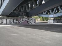 a large graffiti piece on the underside of a bridge with many smaller graffiti pieces attached to it