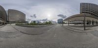 panorama of view into a building at the end of an empty street, with some buildings in the background