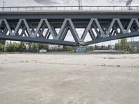 a very large bridge over water near buildings and trees on the other side of the road