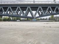 a very large bridge over water near buildings and trees on the other side of the road