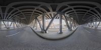 a fisheye shot of a street with a bridge in the background under a very high angle bridge