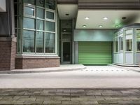 a building with a green gate and some windows and lights on the side of it