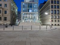 an empty plaza with many buildings and pillars in the background at night time near a city