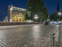 a sidewalk and light posts in a city at night in a big city in europe