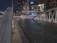 a stone walkway at night next to a building and car light trail in the background