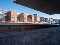 a stone walkway leading to a building in a city with brick pavers under it