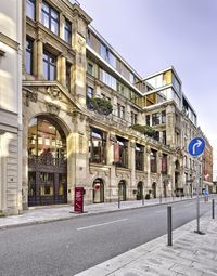 an empty street lined with buildings next to an empty city sidewalk at sunset light,