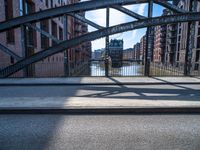 a view of a bridge leading to buildings across the river with a bicycle attached to the end