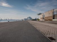 a large concrete road near a factory building and the water below it with the harbor behind it