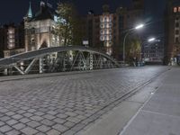 two people walking across a brick walkway in front of a cathedral at night with their bike