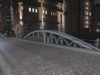 two people walking across a brick walkway in front of a cathedral at night with their bike