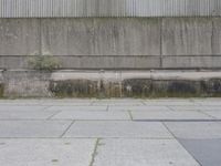 the concrete wall of a warehouse building on a street with a fire hydrant on it