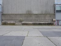 the concrete wall of a warehouse building on a street with a fire hydrant on it