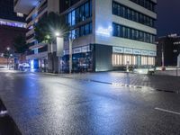 a deserted street has no traffic lights on the building behind it and lights on both sides