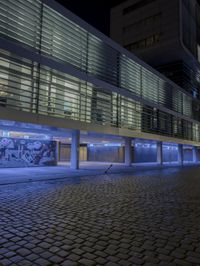 a picture of a large building at night in the city in a large courtyard at the building's edge