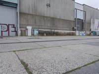 an empty cement sidewalk next to a building covered in graffiti paint and grafitti