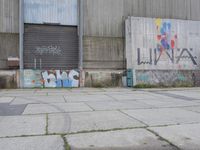 an empty cement sidewalk next to a building covered in graffiti paint and grafitti