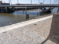 the walkway near the river is lined with brick slabs, and two red lanterns are on each