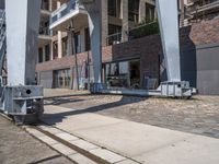 a train moving down the road under a bridge near buildings and a craner truck