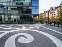 the sidewalk is painted with decorative designs near a building's windows and bicycle racks