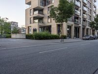 street and trees near the side of the road in front of a brick building with balcon